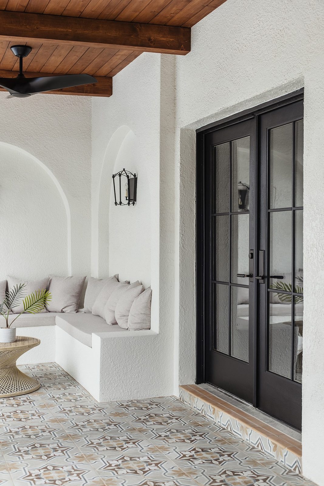 spanish style porch with wood beam ceiling, patterned tile and black french doors