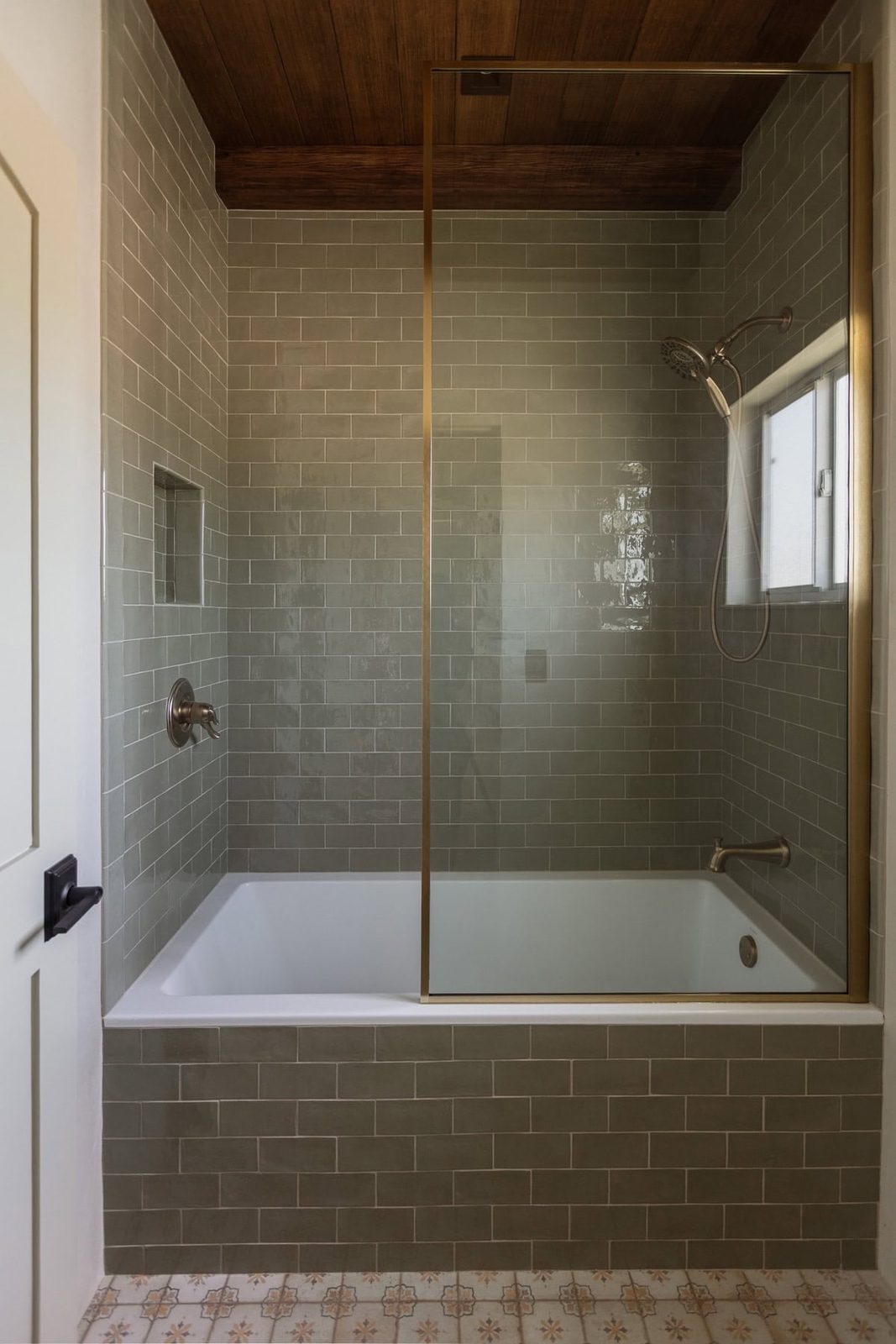 brass shower screen with sage green subway tile