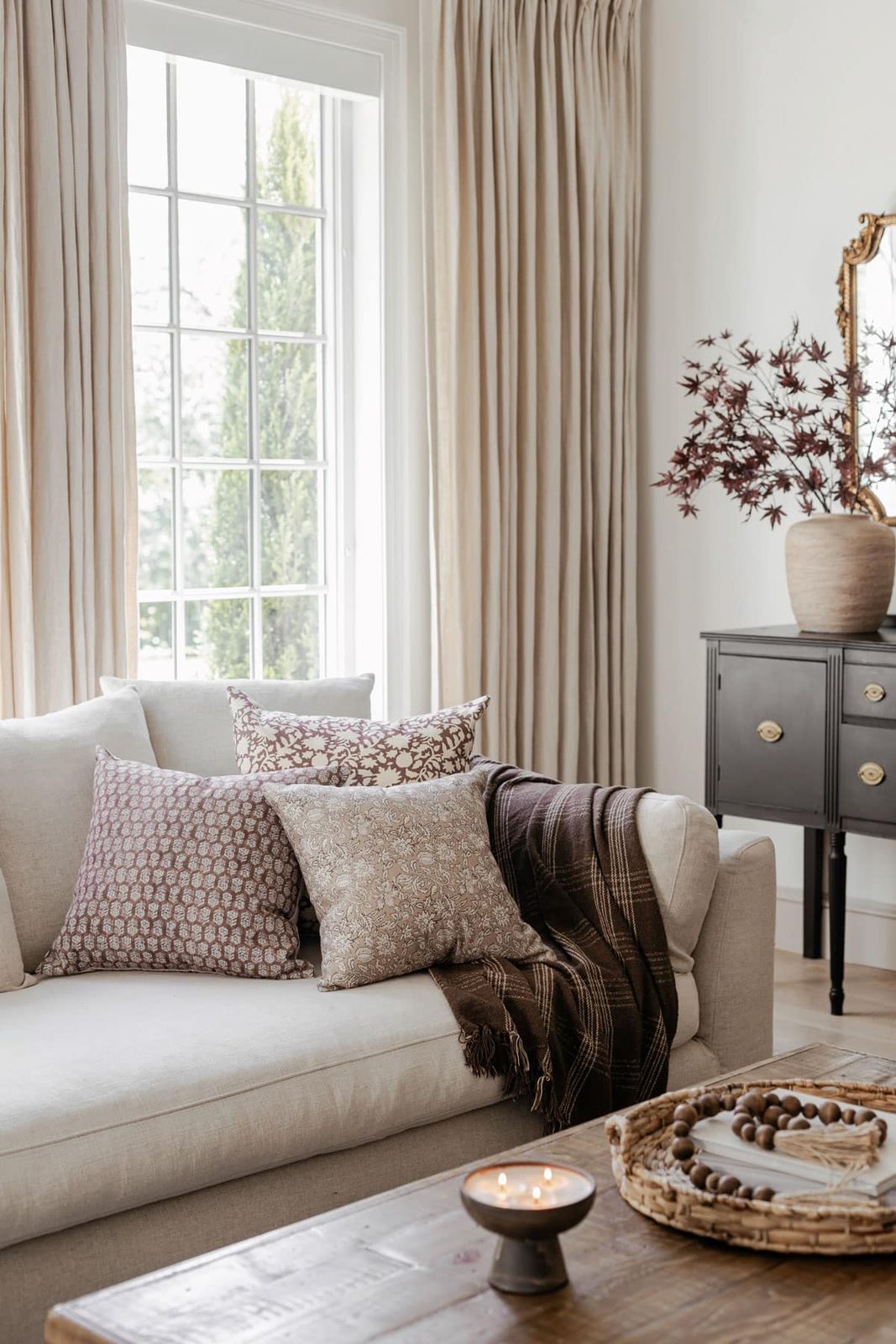 cozy neutral fall living room with pillows, blanket, candle