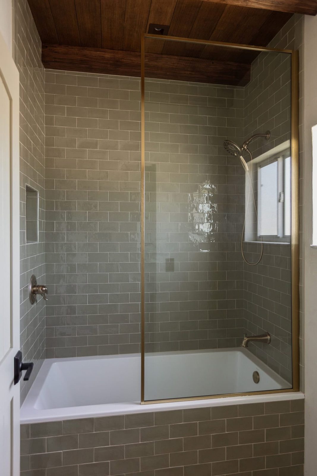 gold shower screen with green subway tile
