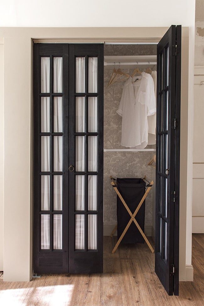 closet with black french glass doors and fabric with wallpaper