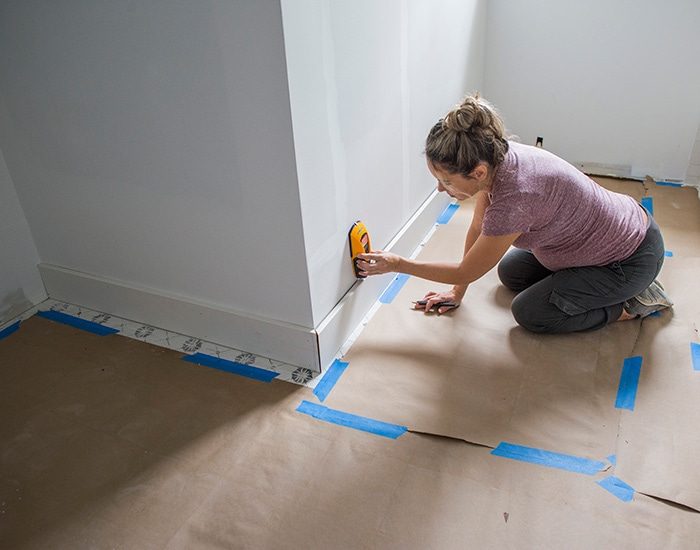 using a stud finder to find studs along the baseboard